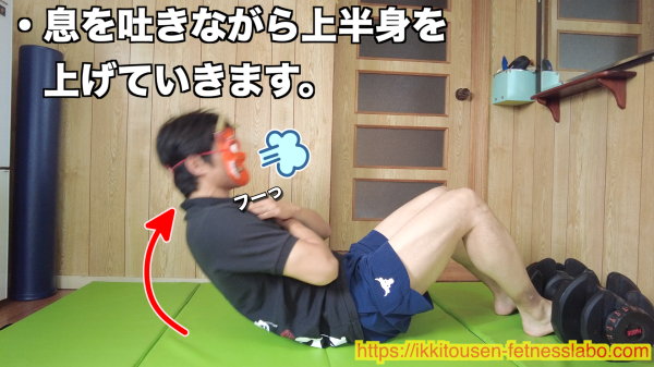 息を吐きながら上体を起こしてシットアップをする男性