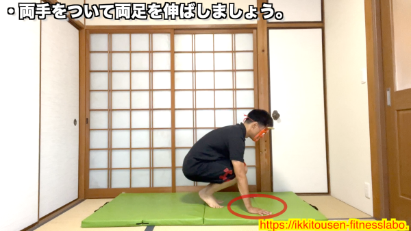 ムエタイバーピーでしゃがみ込み、両手を床について足を伸ばす準備をしている男性