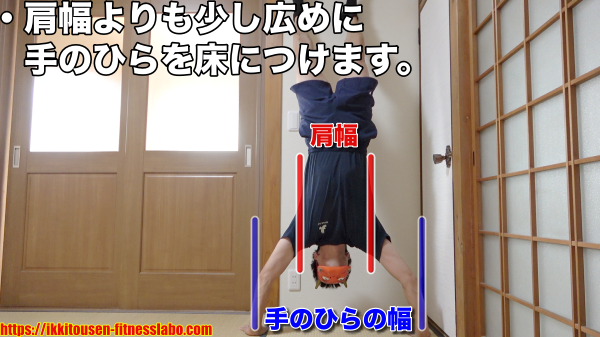 壁あり逆立ち腕立て伏せで、手のひらを肩幅より少し広めについている様子